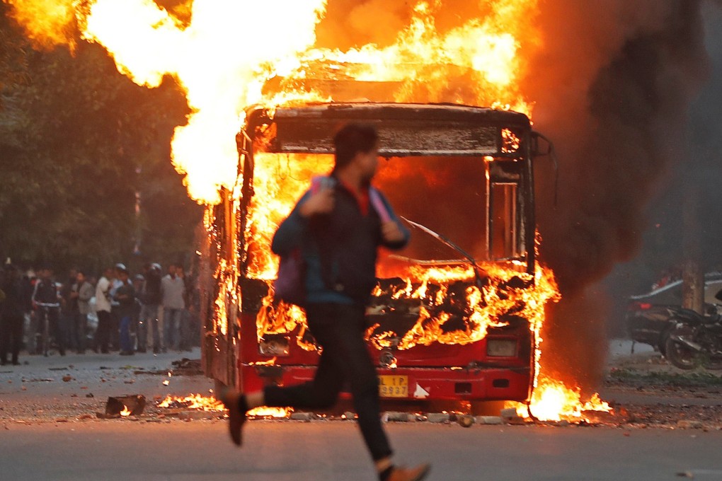 A man runs past a burning bus set on fire by demonstrators against India’s new religion-based citizenship law. Photo: Reuters