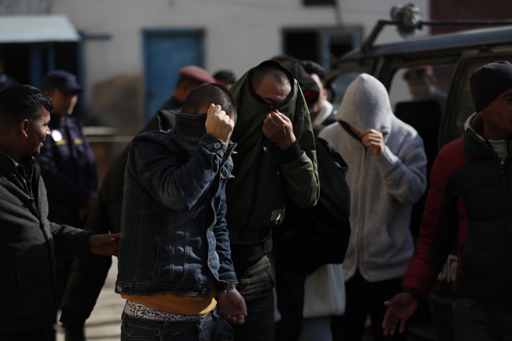 Detained Chinese nationals cover their faces as they are taken to a court in Kathmandu. Photo: AP