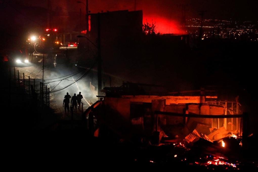 People walk away from a burning house in Valparaiso, Chile, on Tuesday. Photo: EPA-EFE