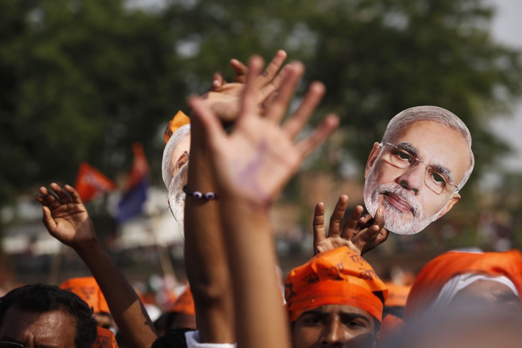 A supporter of India’s Hindu nationalist Bharatiya Janata Party holds up a mask of Prime Minister Narendra Modi. Photo: AP