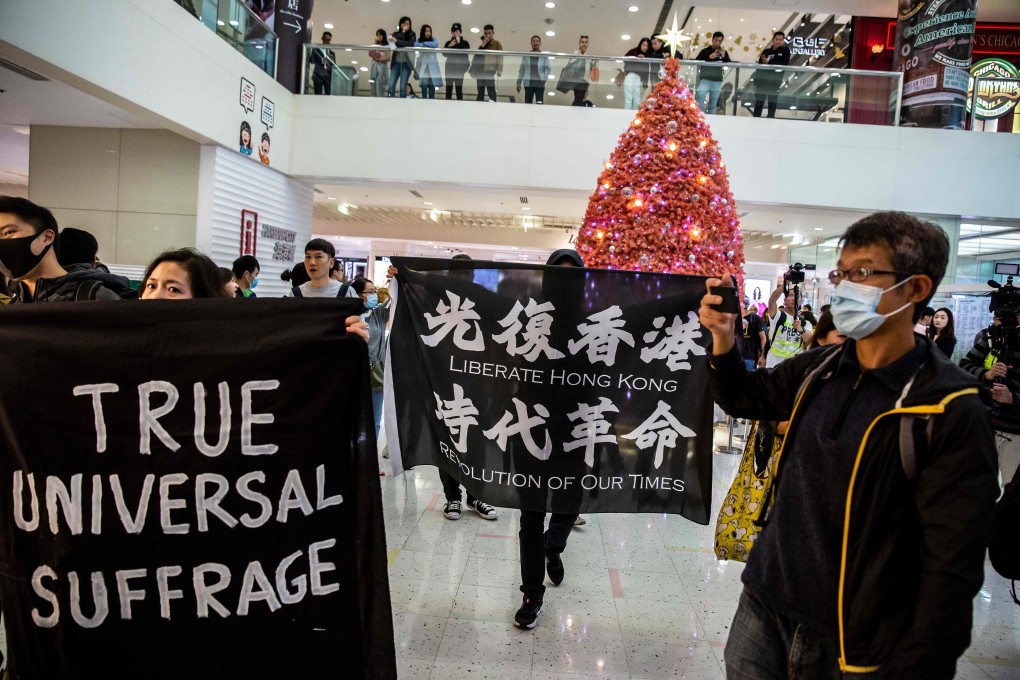 Protesters walk past a Christmas tree as they march through Harbour City, a shopping mall in Tsim Sha Tsui, on December 21. Photo: AFP
