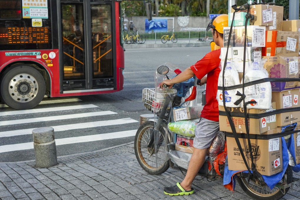 A delivery driver waits at a traffic light to cross the pedestrian crossing in the Futian district in Shenzhen. Photo: Roy Issa