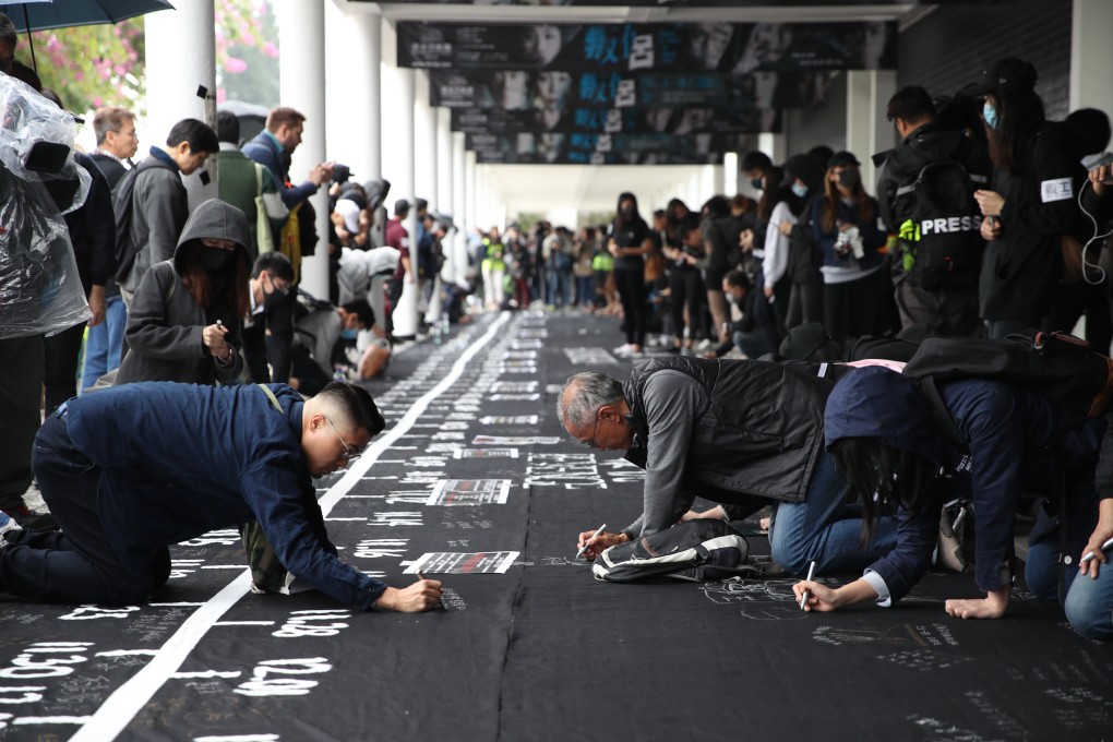 Anti-government protesters write slogans on a giant black banner in Edinburgh Place. Photo: Winson Wong