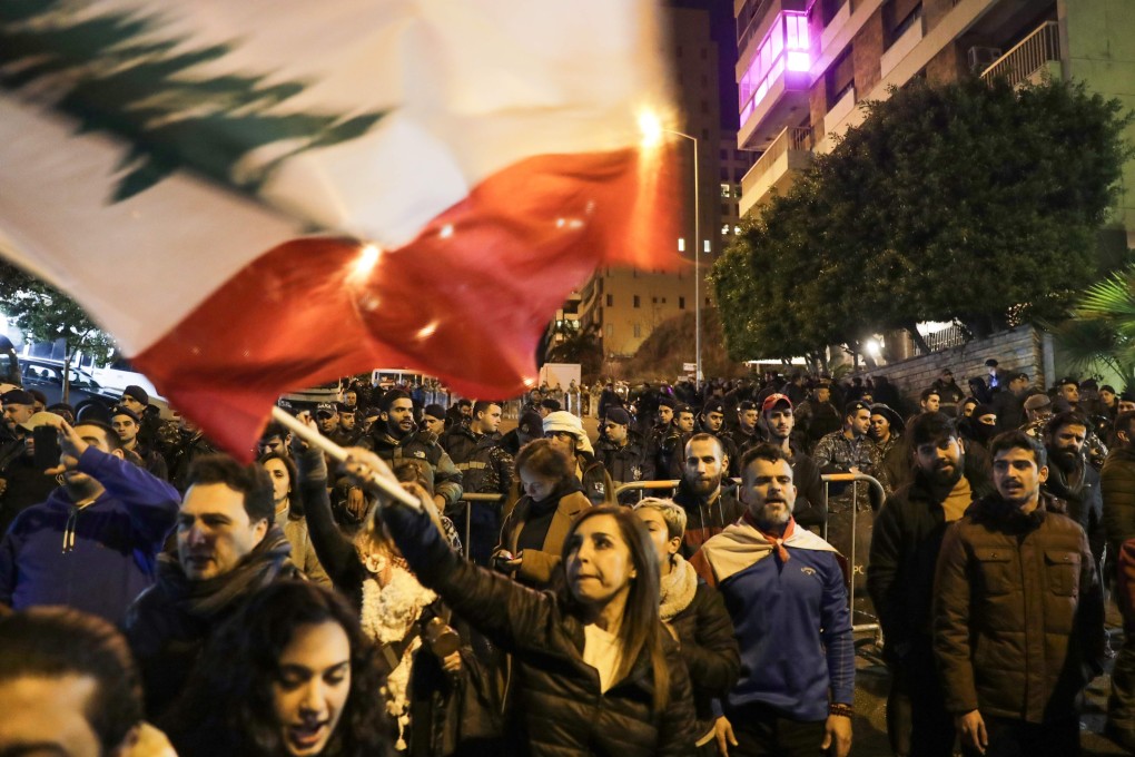 Lebanese protesters wave the national flag as they gather outside the house of Lebanon's new prime minister in the capital Beirut, calling for resignation less than 10 days after he was appointed, on December 28, 2019. - Protests continued after the resignation of the previous prime minister, while political parties negotiated for weeks before nominating Hassan Diab, a professor and former education minister, to replace him on December 19. (Photo by ANWAR AMRO / AFP)
