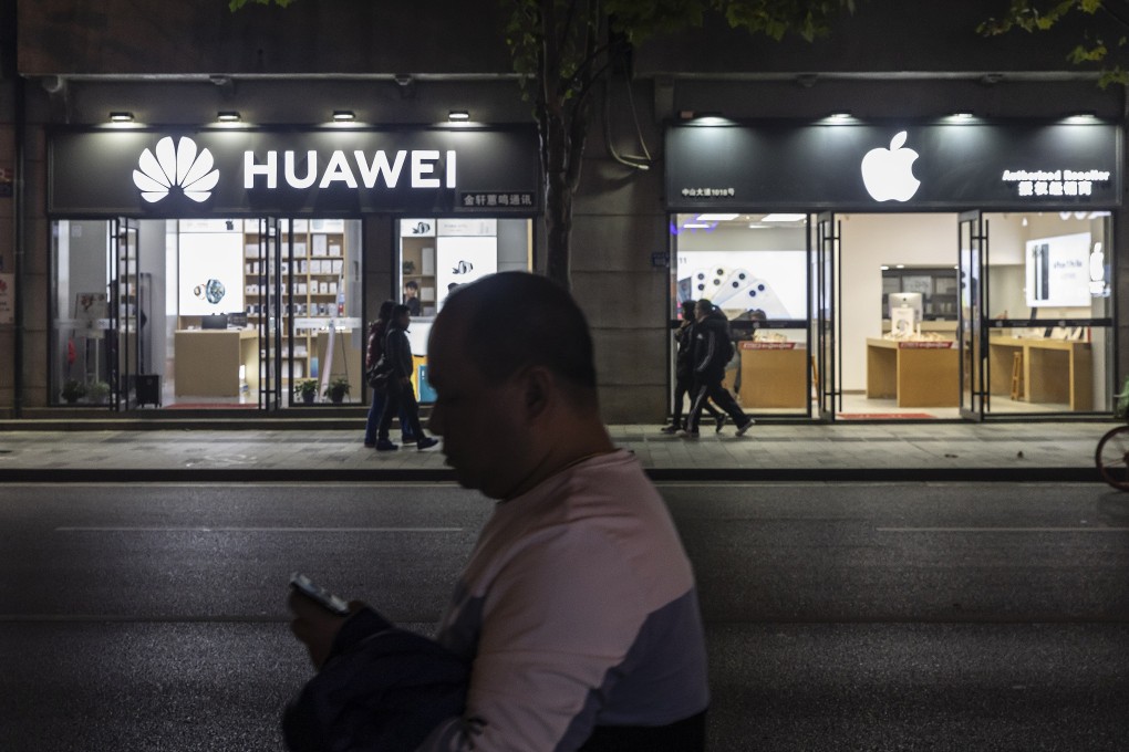 Pedestrians walk past Huawei and Apple stores at night in Wuhan, Hubei province. In 2020, China’s real GDP growth is likely to dip below 6 per cent per year. Photo: Bloomberg