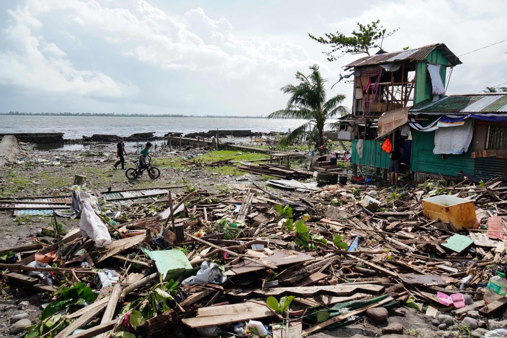 People walk past a house that was damaged during Typhoon Phanfone in Tacloban, Leyte province in the central Philippines. The number of deaths has risen to 41, with 12 unaccounted for. Photo: AFP