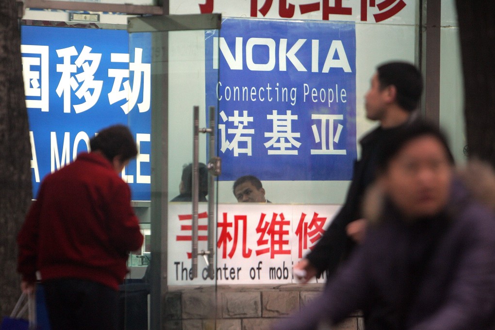 Pedestrians pass a shop selling mobile phones in Beijing, April 1, 2007. The ubiquity of mobile apps was built on the popularity of smartphones, which signalled a new era when the Android operating system overtook Nokia’s Symbian in 2012. Photo: AFP
