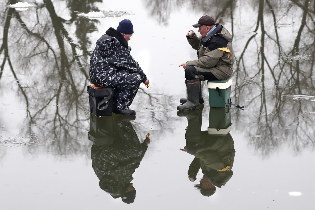 Russian men fish on a pond covered in thin ice in Moscow earlier this month. Photo: EPA