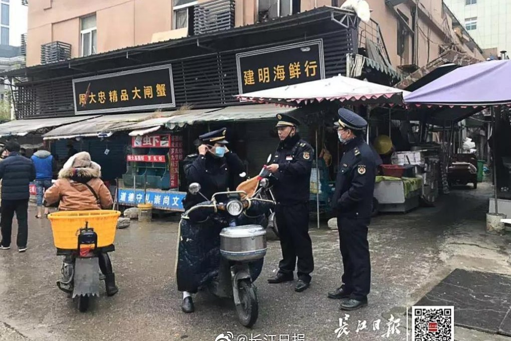 Law enforcement officers stand guard outside the seafood market in Wuhan that was ordered to close after a mystery flu outbreak. Photo: Yangtze Daily