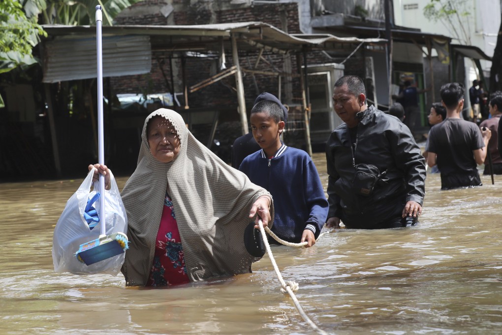 Residents hold a lead rope as they wade through a flooded neighbourhood in Tanggerang outside Jakarta, on January 2, 2020. Photo: AP