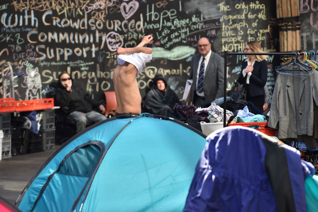 A homeless man gets dressed outside his tent in Sydney’s central business district. The area, known as Tent City, was cleared in 2017, but not before igniting a national debate on homeless people and soaring prices in Australia. Photo: AFP