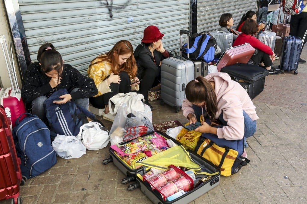 Mainland tourists with suitcases full of shopping sit on the pavement in Sheung Shui. Photo: Dickson Lee