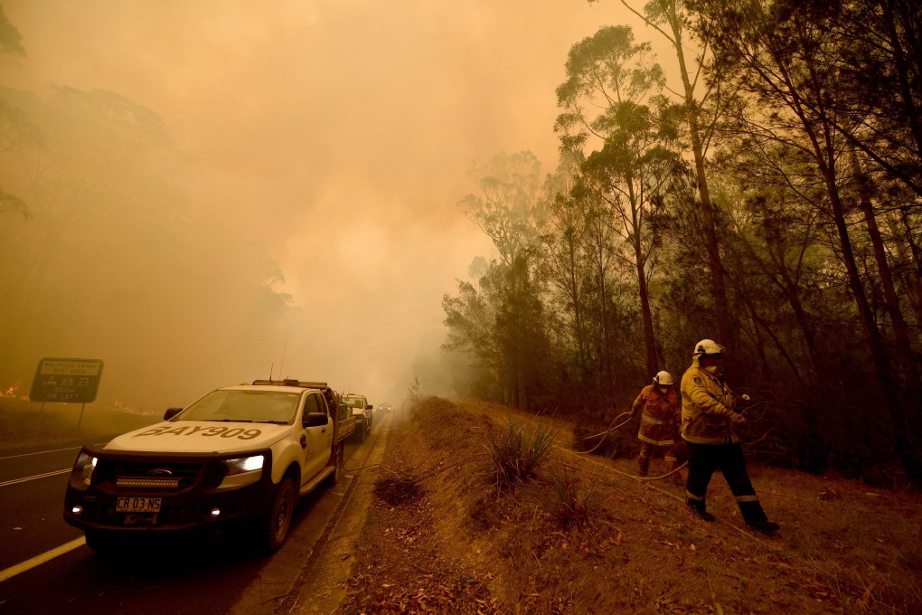 Firefighters tackle a bush fire in thick smoke in the town of Moruya, south of Batemans Bay in New South Wales. Photo: AFP