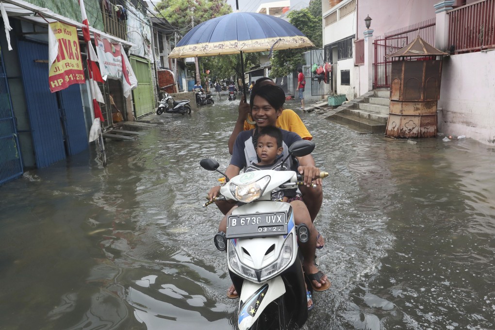Jakarta residents ride on a flooded street after torrential downpours caused floods that left dozens of people dead and increased the risk of diseases such as dengue and leptospirosis. Photo: AP