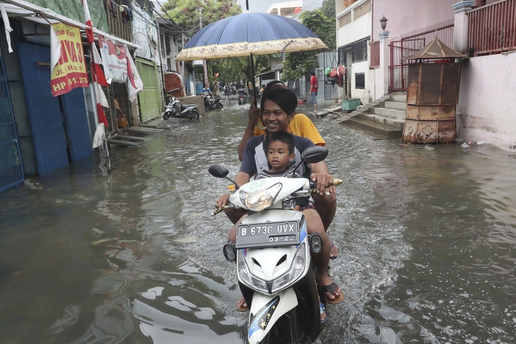 Jakarta residents ride on a flooded street after torrential downpours caused floods that left dozens of people dead and increased the risk of diseases such as dengue and leptospirosis. Photo: AP