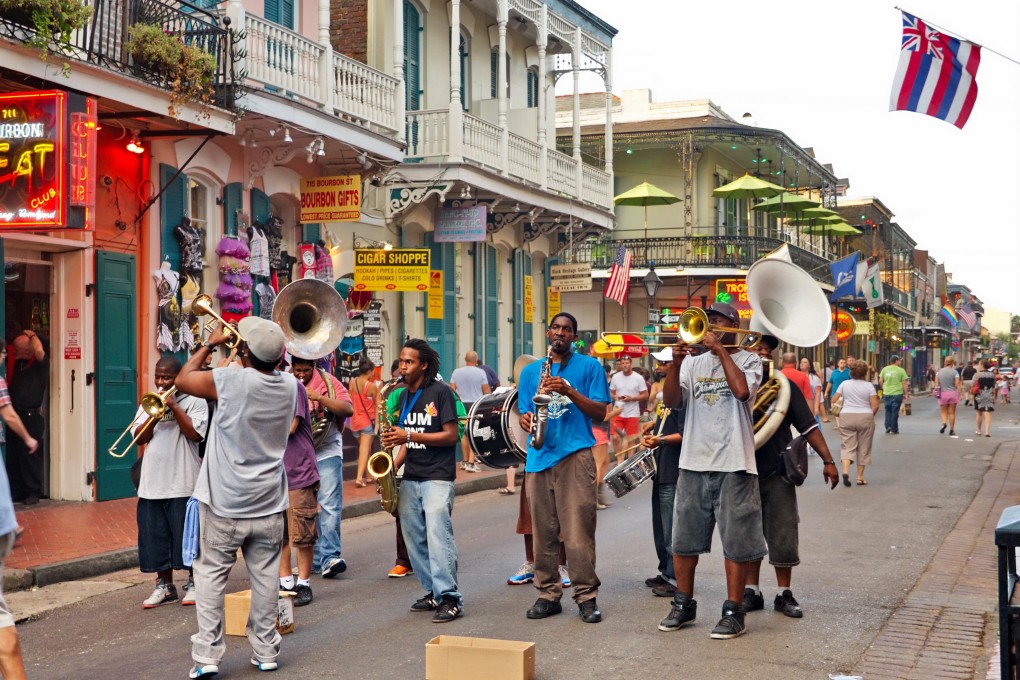 Bourbon Street in the French Quarter of New Orleans, and a “second line” jazz band parades seeking donations from tourists and locals. Photo: Shutterstock