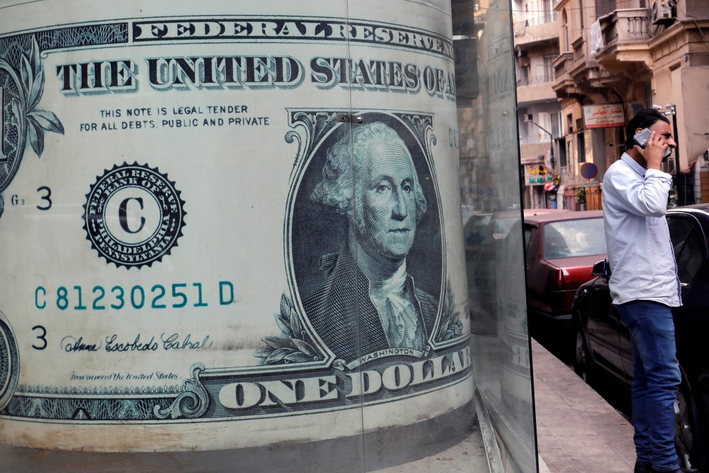 A man talks on his mobile phone in front of a currency exchange bureau advertisement showing images of the US dollar in Cairo. The dollar has had a good run for its money over the past few years on the strength of the “Trump effect”. Photo: Reuters