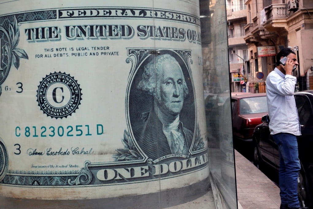 A man talks on his mobile phone in front of a currency exchange bureau advertisement showing images of the US dollar in Cairo. The dollar has had a good run for its money over the past few years on the strength of the “Trump effect”. Photo: Reuters
