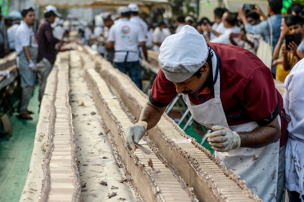 A baker works on an approximatively 6.5km-long cake in the south Indian state of Kerala on Wednesday. Photo: AFP
