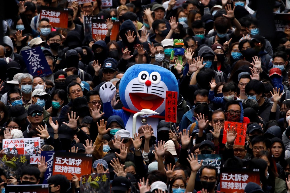 A protester in a Doraemon costume joins a march on New Year’s Day, with demonstrators holding up their hands to call for better governance and democratic reforms in Hong Kong. Photo: Reuters