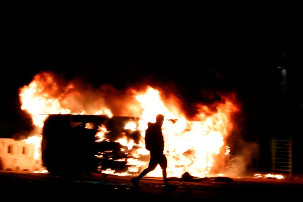 An anti-government protester walks past a burning vehicle during a protest in Tseung Kwan O, Hong Kong, on November 11, 2019. Photo: Reuters