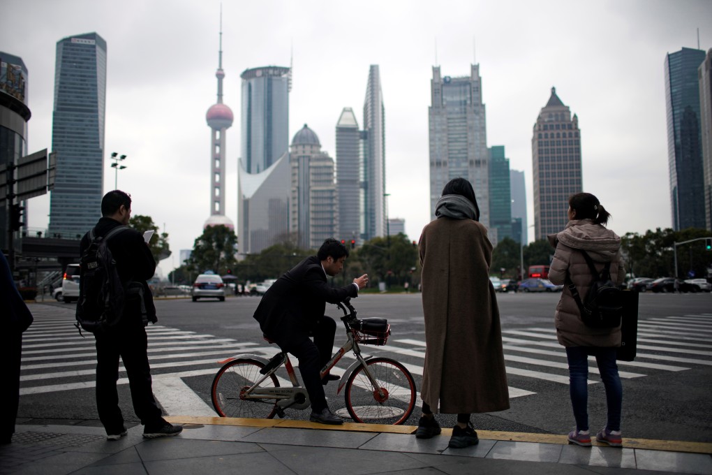 People waiting to cross the street check their smartphones in the financial district of Pudong in Shanghai. Photo: Reuters