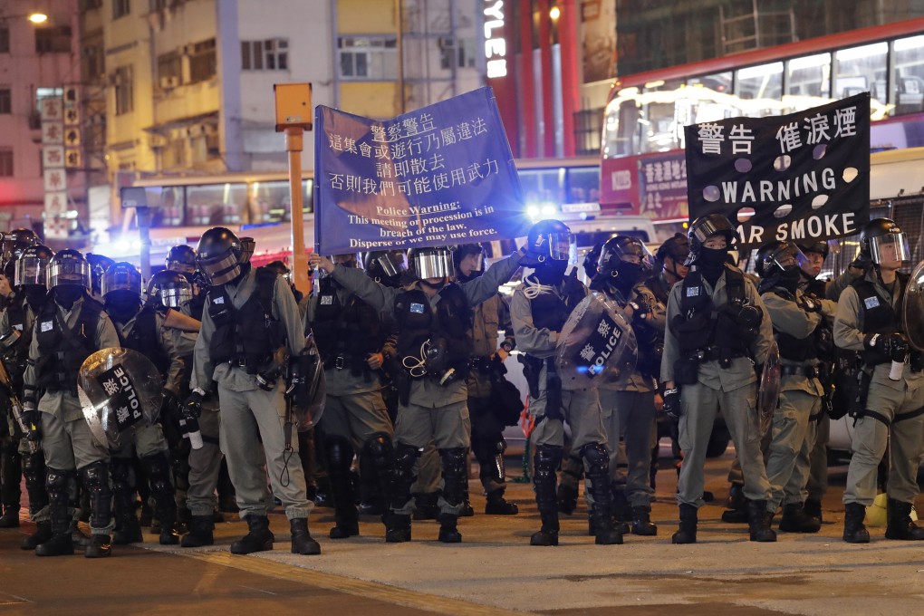 Hong Kong riot police hold up banners warning of imminent tear gas deployment, as they urge demonstrators taking part in an “unlawful assembly” to disperse, on December 25. Photo: AP