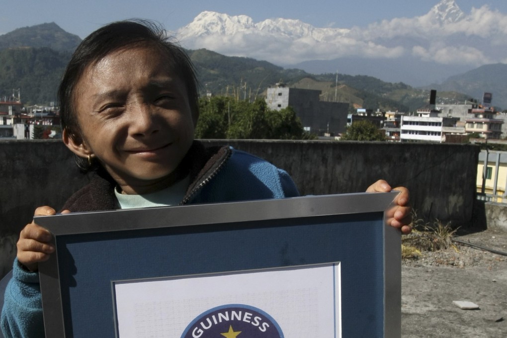 Khagendra Thapa Magar, the world's shortest man, poses with his Guinness record certificate against the backdrop of Mount Machchhapuchhre in Pokhara, Nepal, in October 2010. Photo: AFP