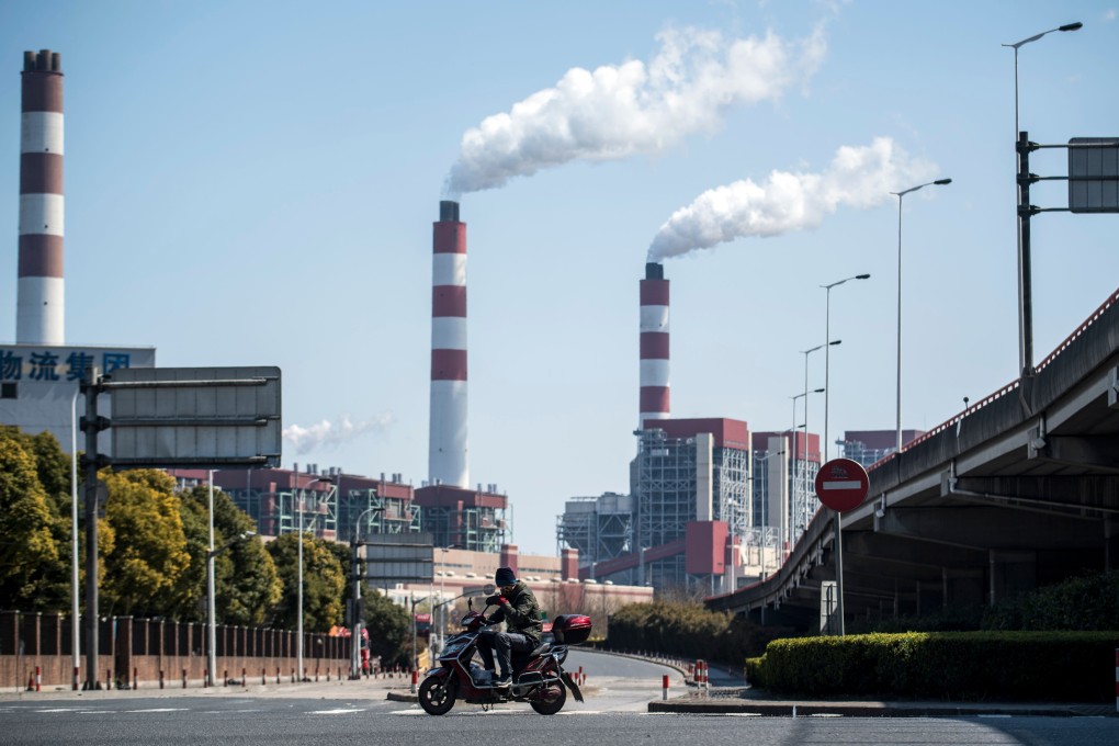 A man rides his scooter near the a coal power plant in Shanghai. Photo: AFP