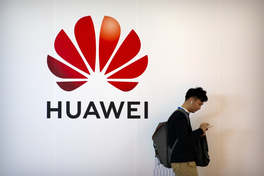 A man uses his smartphone as he stands near a billboard for Chinese technology firm Huawei at the PT Expo in Beijing, 2020. Photo: AP