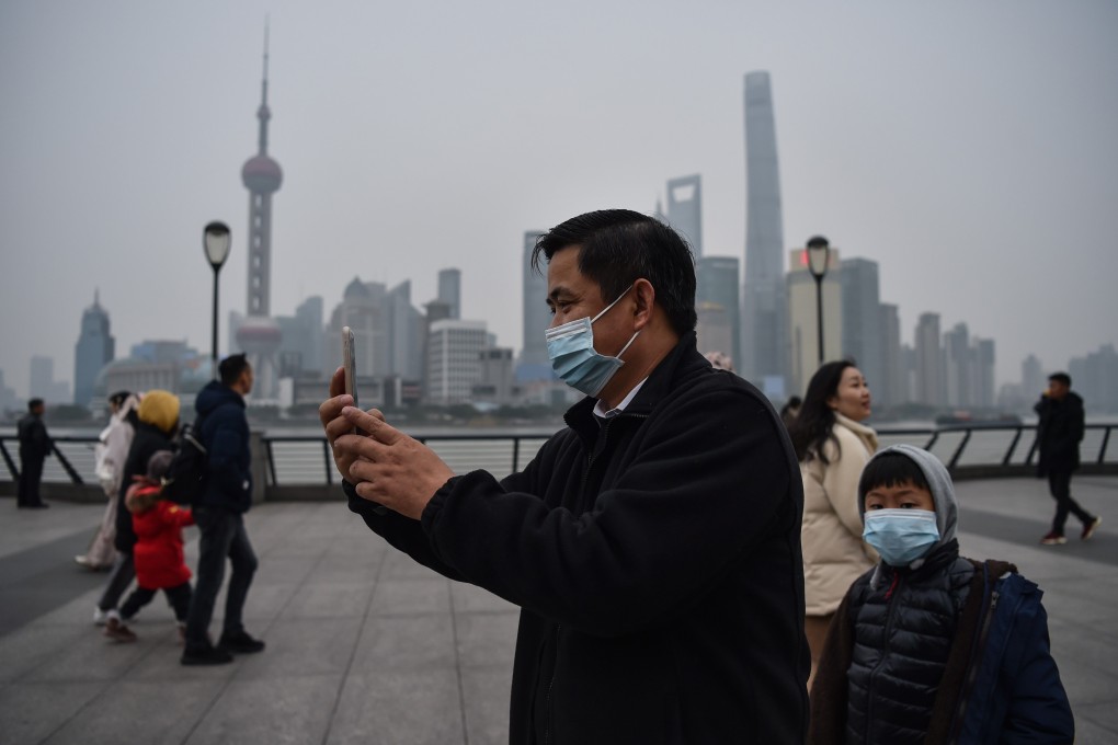 A man wearing a protective mask takes pictures on the promenade of the Bund along the Huangpu River in Shanghai on January 21, 2020. Photo: AFP
