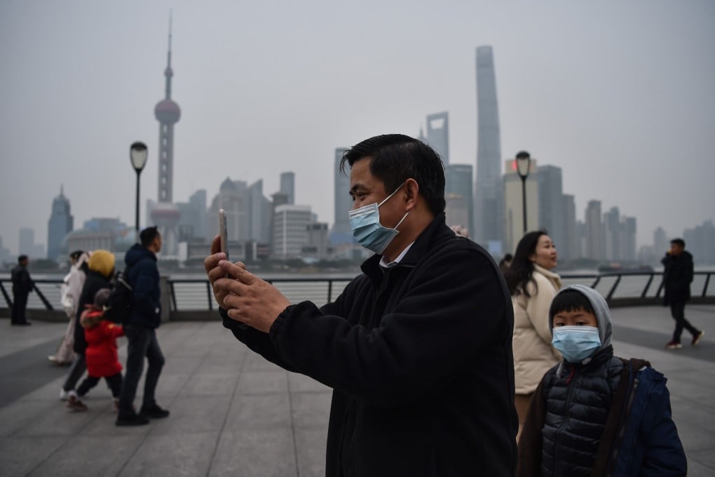 A man wearing a protective mask takes pictures on the promenade of the Bund along the Huangpu River in Shanghai on January 21, 2020. Photo: AFP