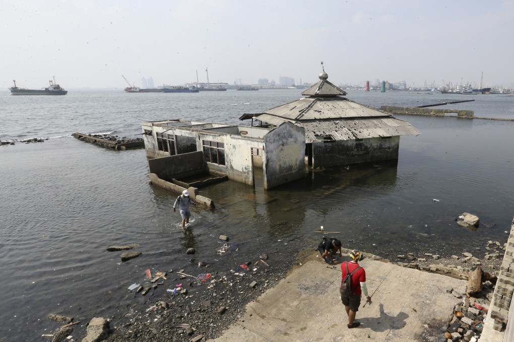 People walk near a sea wall in Jakarta, one of the world’s fastest-sinking cities. Photo: AP
