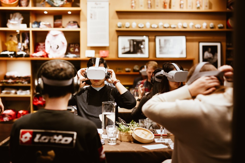Guests wear virtual reality headsets at a Studio ATAO dinner. The VR segments diners see are meant as cues to get them to talk about issues they might not otherwise discuss. Photo: Briana Balducci