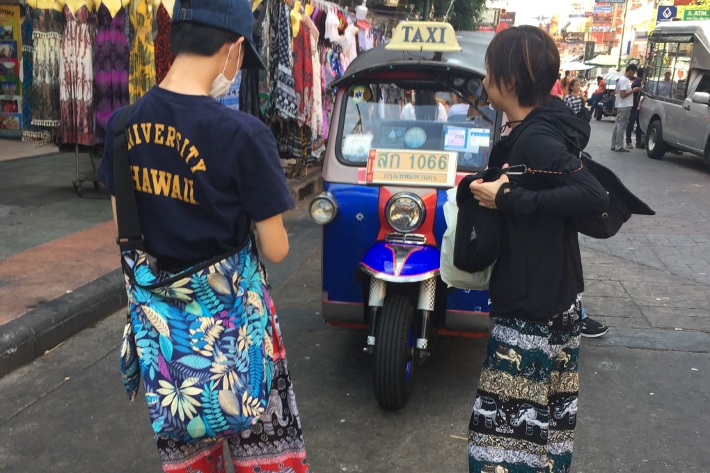 Tourists wear ‘elephant pants’ in front of a tuk-tuk in Bangkok. Photo: DPA