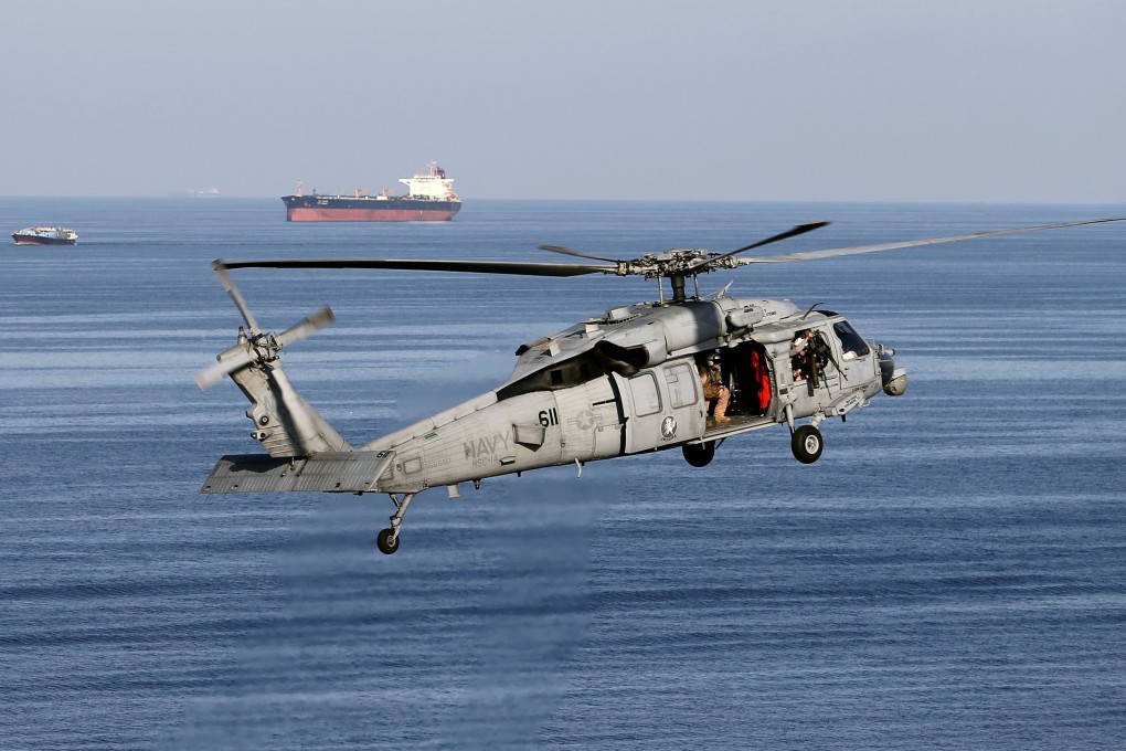 A MH-60 helicopter hovers in the air with an oil tanker in the background. Photo: Reuters