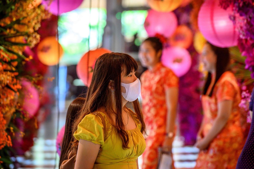 A woman with a face mask walks through a shop decorated for the Lunar New Year in Bangkok on January 24, after five people were detected with the coronavirus in Thailand. Photo: AFP