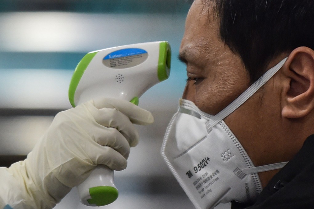 A medical worker checks the temperature of a Wuhan resident as scientists rush to develop a vaccine for the coronavirus in China. Photo: AFP