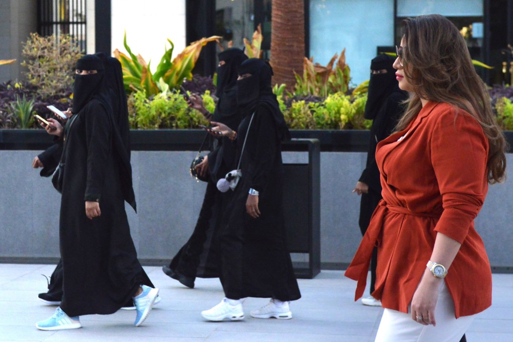 A Saudi woman wearing Western clothes walks past other women wearing conservative clothing in the capital, Riyadh. Photo: AFP