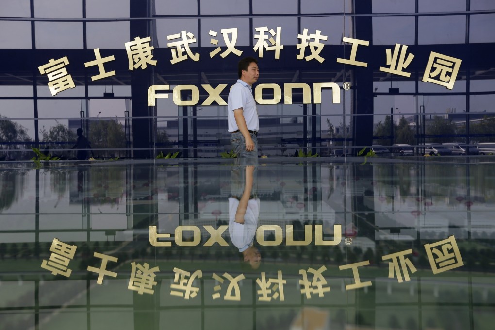 A man walks past the logo of Foxconn Technology Group at a factory in Wuhan, Hubei province. Photo: Reuters