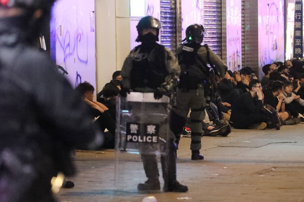 Police stand guard over people arrested amid a New Year march in Hong Kong. Photo: Dickson Lee