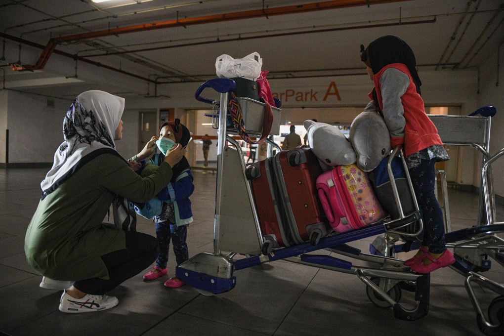 A woman adjusts a face mask on her child at Kuala Lumpur International Airport. Malaysia banned visitors from the Chinese city of Wuhan and its surrounding Hubei province on January 27 in a bid to contain the spread of a deadly virus. Photo: AFP