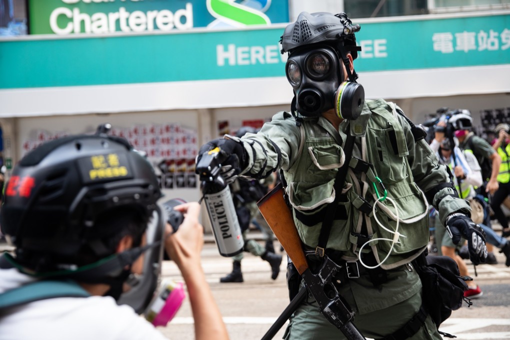 A riot police officer aims pepper spray at a journalist during a protest in Hong Kong’s commercial district of Causeway Bay, in September 2019. Photo: Bloomberg