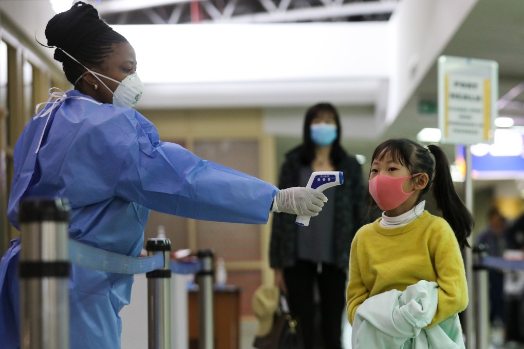A Kenyan health worker screens a young passenger upon her arrival from China at Jomo Kenyatta International Airport in Nairobi on Wednesday. Photo: EPA-EFE