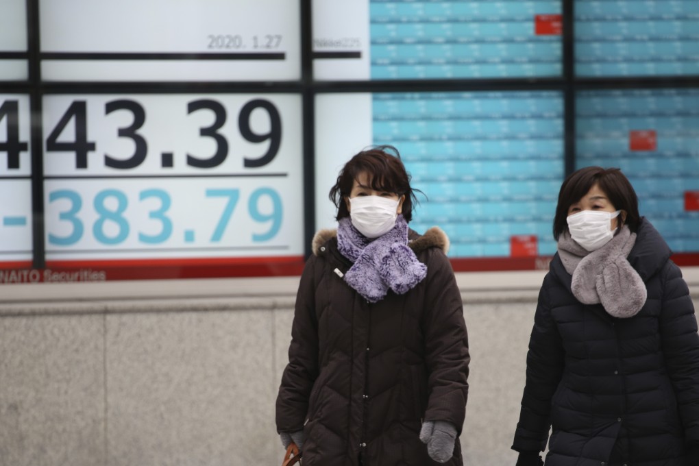 People walk by an electronic stock board of a securities firm in Tokyo on January 27. Shares tumbled in the few Asian markets open as China announced sharp increases in the number of people affected by an outbreak of a new coronavirus. Photo: AP