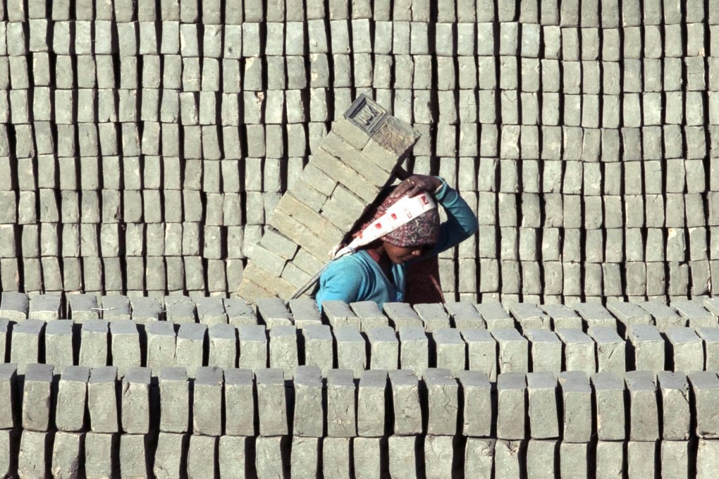 A Nepalese worker carries uncooked bricks at a factory. File photo: EPA