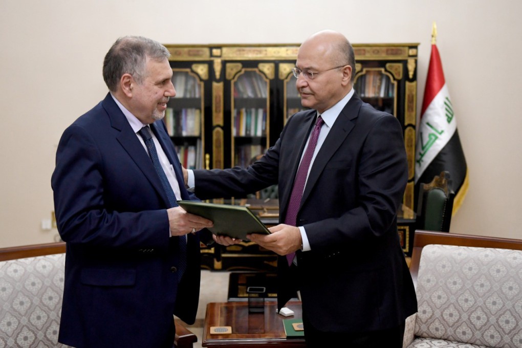 President Barham Salih (R) presenting Mohammad Allawi, a former communications minister and lawmaker, with the decree to appoint him as Iraq's new premier. Photo: Handout via AFP