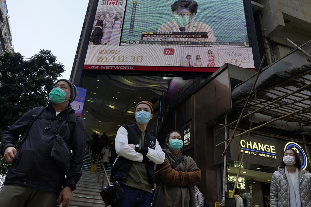 People in masks in front of a screen broadcasting a message by Hong Kong Chief Executive Carrie Lam. Photo: AP