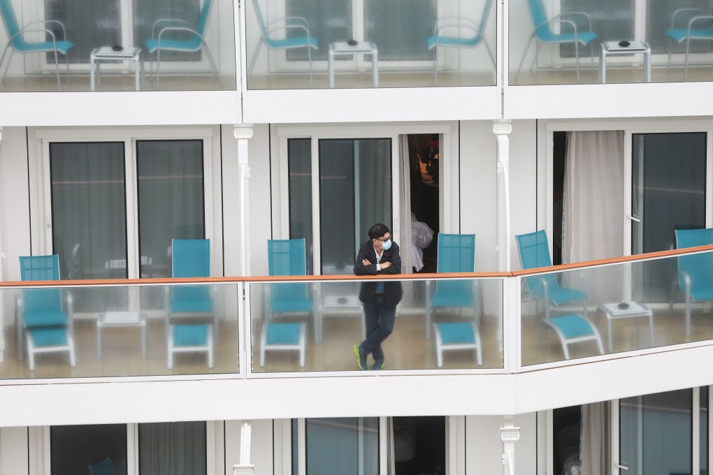A passenger wearing a mask stands on a balcony on the World Dream after it docked at Kai Tak Cruise Terminal. Photo: Sam Tsang