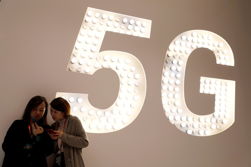 Visitors use their smartphones as they stand next to a large 5G display inside Xiaomi Corp’s booth at MWC Barcelona, the world’s biggest mobile industry exhibition, in Spain in February of last year. Photo: Reuters